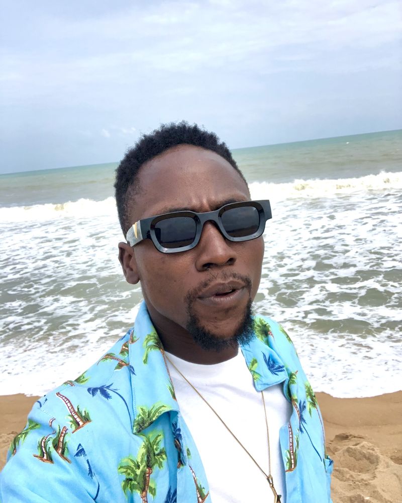 Victor in sunglasses and a palm-print shirt on a beach