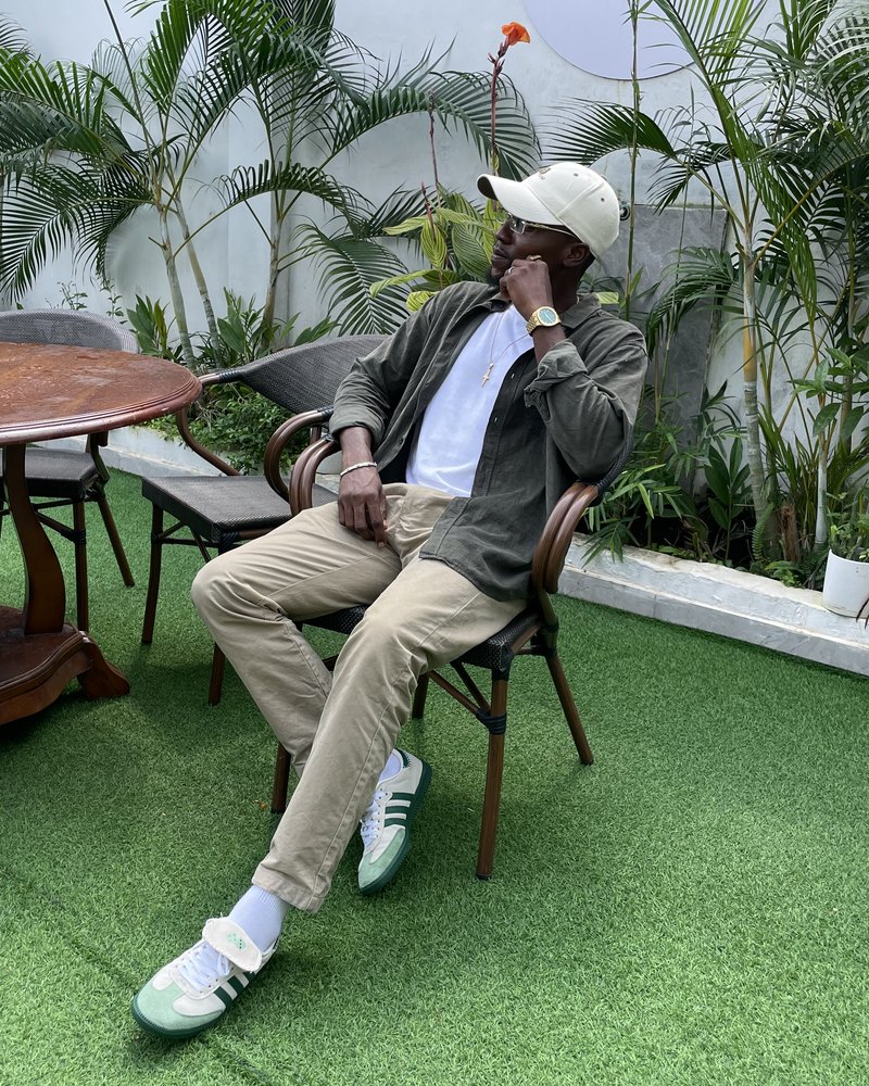 Victor sitting in a garden in a cap and olive overshirt